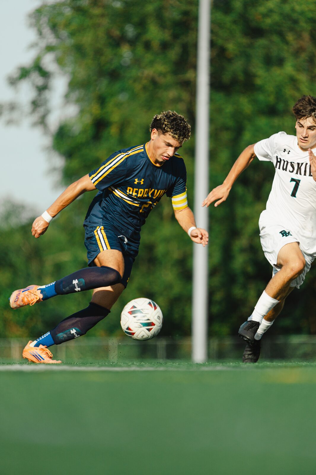 Soccer player leaping off the ground to strike the ball out of the air in golden evening light